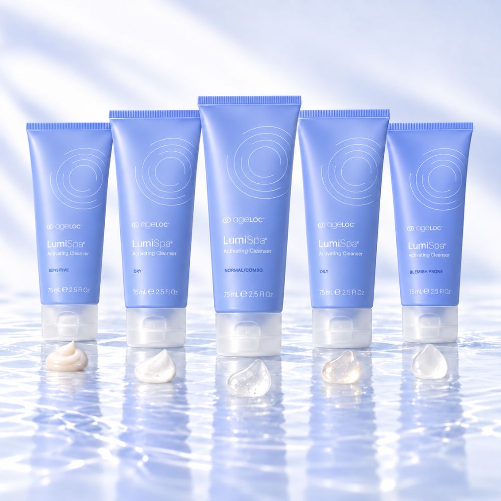Five light blue tubes of Aigleloc LumiSpa activating Cleanser arranged in a row on a reflective icy surface with small dollops of cream in front. The tubes feature white text and circular line graphics, set against a cool, light blue background with soft shadows.