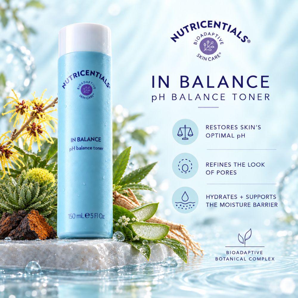A bottle of Nutricentials In Balance pH Balance Toner stands on a stone pedestal in a water-themed setting with green leaves and yellow flowers. The bottle is light blue with a white cap.