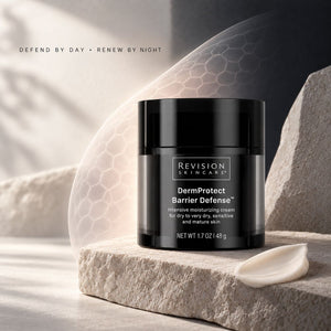 A black jar of Revision Skincare DermProtect Barrier Defense moisturizing cream sits on a textured stone slab with a small smear of cream beside it. The background is a soft, warm gray and white with abstract shadows and a faint hexagonal pattern, and the text 'DEFEND BY DAY • RENEW BY NIGHT' appears at the top left.