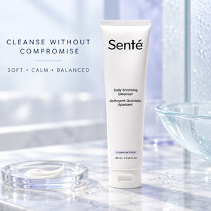 A white squeeze tube of Sente Daily Soothing Cleanser stands on a light marble surface with a small dish of cream and a glass bowl in a softly blurred bathroom-like setting. Text on the left reads 'CLEANSE WITHOUT COMPROMISE' and 'SOFT • CALM • BALANCED'.