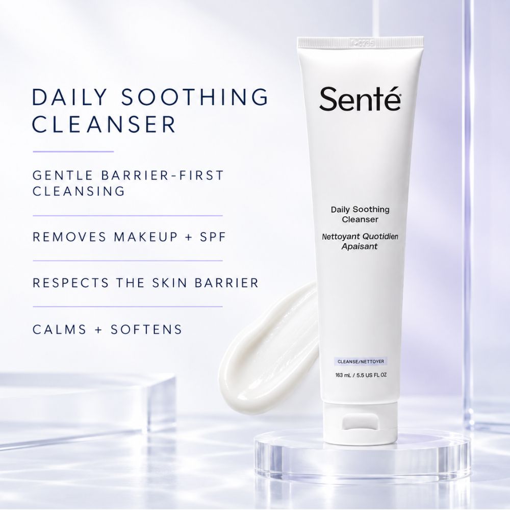 A white tube of Senté Daily Soothing Cleanser stands on a clear acrylic pedestal against a soft white and pale blue studio background, with product text and a smear of cleanser shown to the left.