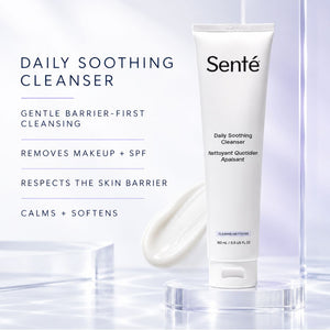 A white tube of Senté Daily Soothing Cleanser stands on a clear acrylic pedestal against a soft white and pale blue studio background, with product text and a smear of cleanser shown to the left.