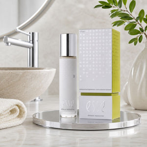 ESSE Defence Moisturiser bottle and packaging box displayed on a round silver tray in a bathroom setting with a sink, mirror, and plant visible in the background.