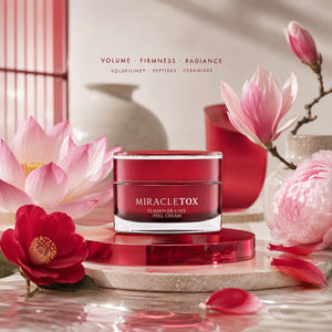 Miracletox Turnover Unit feel Cream in a red jar, styled on a marble slab with pink and red flowers in a warm, elegant setting.