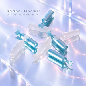 Several Nu Skin Galvanic Spa Facial gel ampoules arranged on a glossy light blue surface with soft glowing light effects. Text in the upper left reads 'PRE-TREAT + TREATMENT' and 'TWO-STEP GALVANIC FACIAL'.