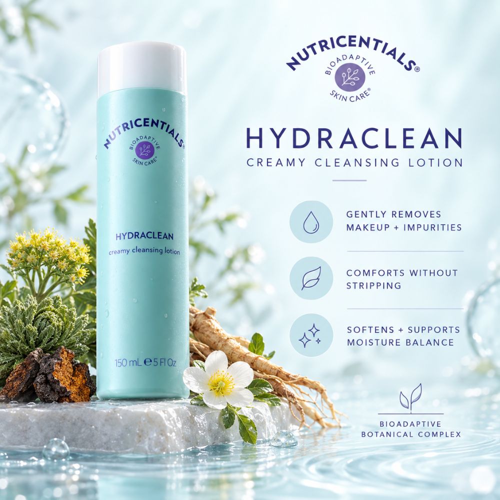 Nutricentials Hydraclean Creamy Cleansing Lotion in a light blue cylindrical bottle with a white cap, displayed on a stone surface with water, bioadaptive plants and a white flower. The image includes product features text on the right side.
