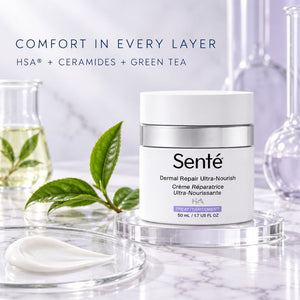 Sente Dermal Repair Ultra-Nourish cream jar on a clear acrylic stand, with a white spoon of cream in the foreground, green tea leaves, and glassware in the background under the text 'COMFORT IN EVERY LAYER'.
